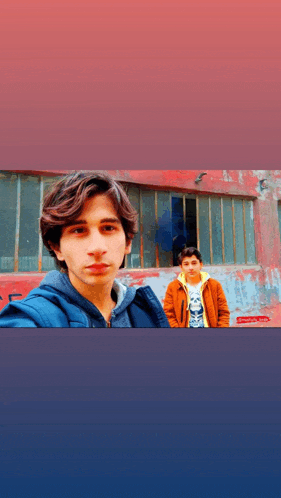 two young men pose for a picture in front of a red wall