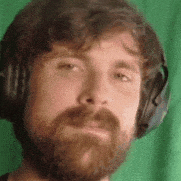 a man with a beard wearing headphones is making a funny face .