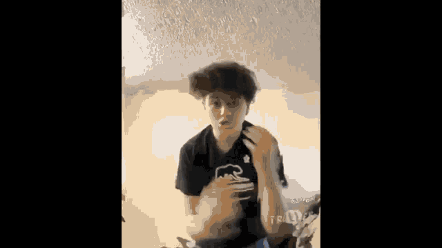 a young man is standing in a room holding a basketball and talking on a cell phone .