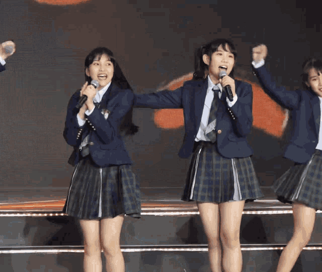 two girls singing into microphones on a stage