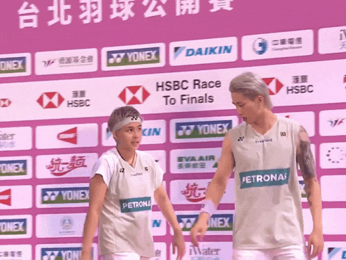 a man and a woman standing in front of a wall that says hsbc race to finals on it