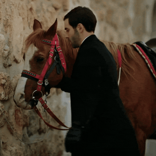 a man stands next to a horse with a red bridle
