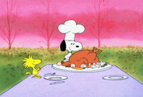 a cartoon of snoopy wearing a chef 's hat standing next to a plate of food