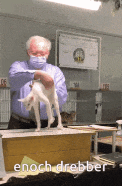 a man holds a white cat in front of a sign that says the cat fanciers association inc.