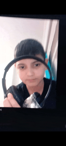 a young boy is holding a pair of headphones around his head