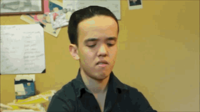 a young man in a black shirt is making a face