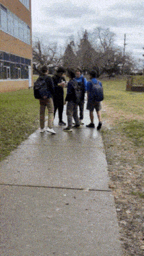 a group of young men standing on a sidewalk talking