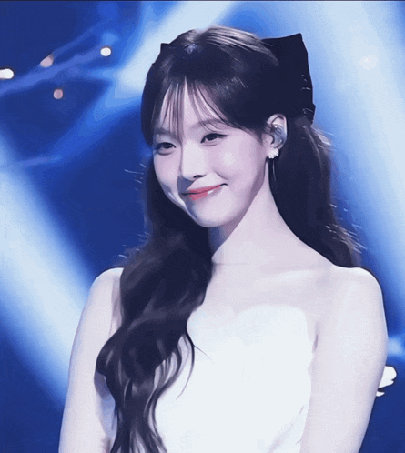 a woman in a white dress with a black bow in her hair smiles