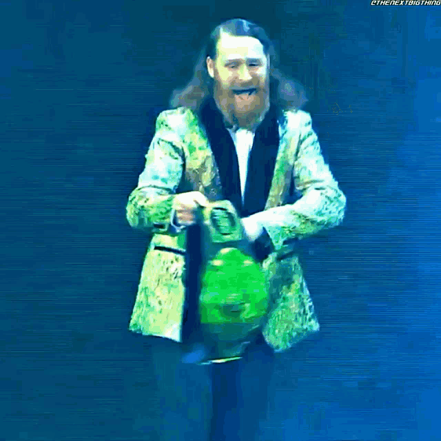 a bearded man in a green suit is holding a trophy in his hands