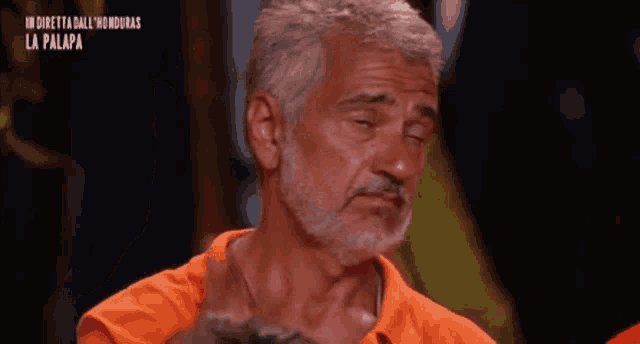 a man with a beard is wearing an orange shirt