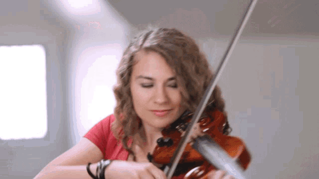 a woman is playing a violin in front of a window