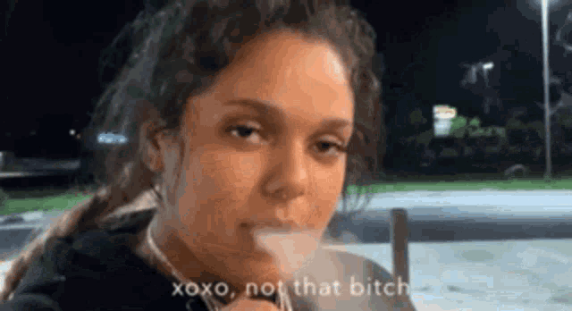 a woman is smoking a cigarette and says " xoxo , not that bitch "