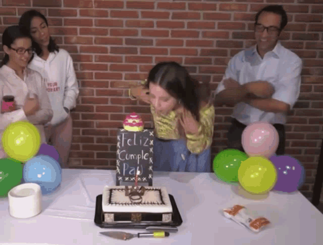 a girl is blowing out candles on a cake that says feliz cumple