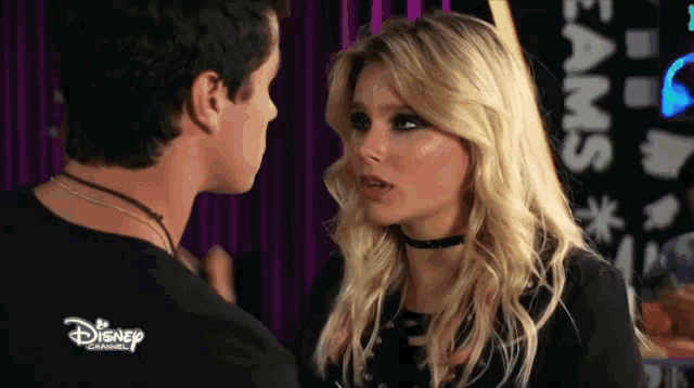 a man and a woman are looking at each other with a sign in the background that says disney channel