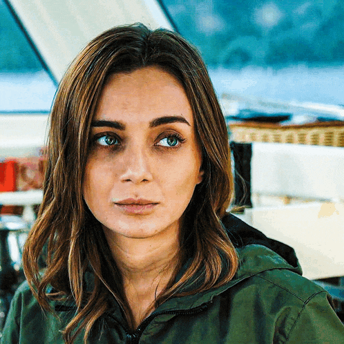 a close up of a woman 's face with a green jacket on