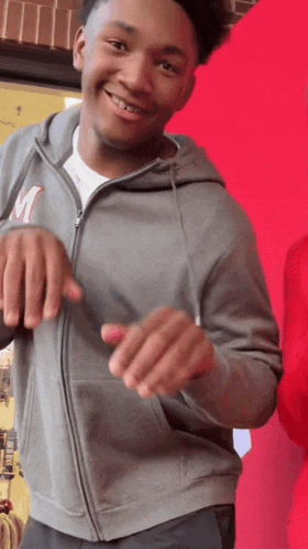 a young man wearing a gray hoodie with the letter m on it