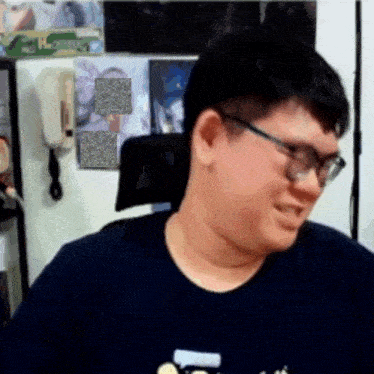 a man wearing glasses and a blue shirt is sitting in a chair