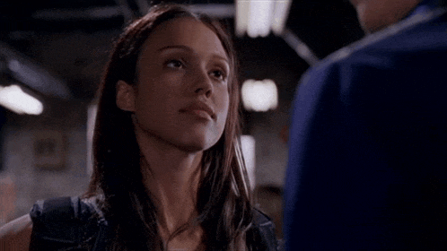 a close up of a woman looking at a man in a dark room