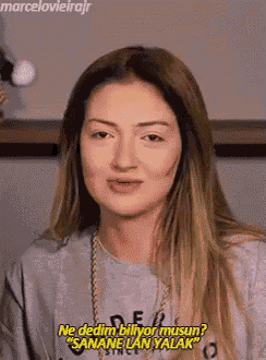 a woman with long hair is wearing a gray sweatshirt and a gold chain .