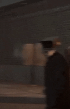 a man is holding a gun in his hand in front of a brick wall .
