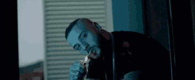 a man is lighting a cigarette with a lighter in his mouth .