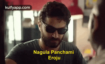 a man wearing sunglasses and a black shirt is talking to another man and says nagula panchami eroju .