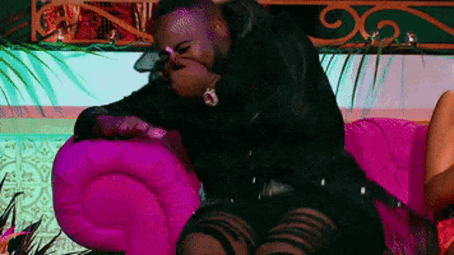 a man is sitting on a pink couch next to a woman