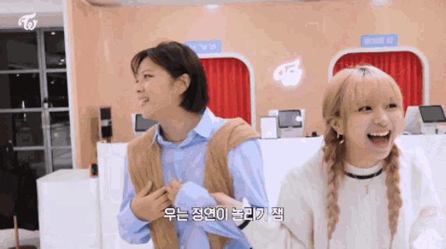 two girls are laughing in front of a sign that says ' twice ' on it