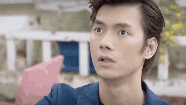 a young man in a blue jacket is looking up at something