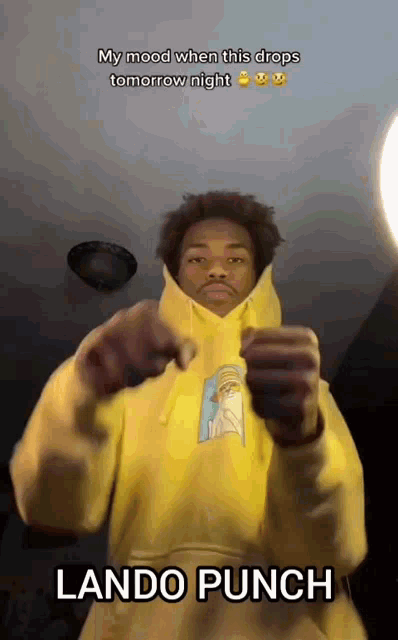a man in a yellow hoodie is making a punch gesture