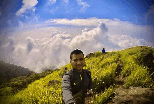 a man wearing a nike vest stands on top of a hill