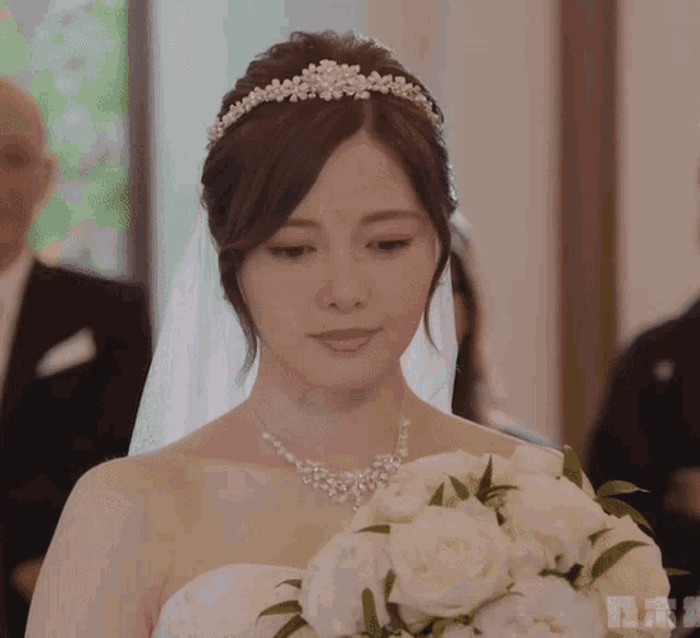 a woman in a wedding dress holds a bouquet of white roses