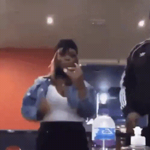 a woman is standing in a room with a bottle of water in the background .