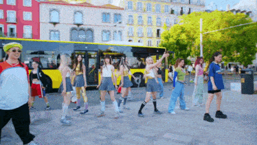 a group of young women are dancing in front of a yellow bus that says ' twice ' on it