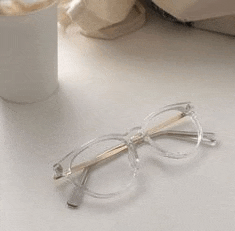 a pair of clear glasses sitting on top of a white table next to a cup of coffee .