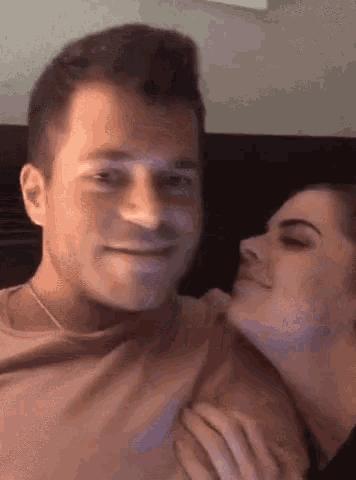 a man and a woman are sitting next to each other and the woman is kissing the man on the cheek