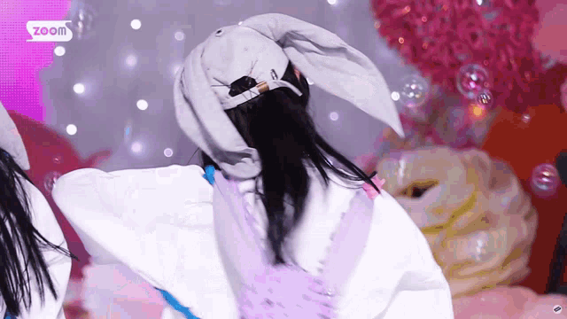 a girl wearing a hat with bunny ears is dancing in front of a pink background that says zoom