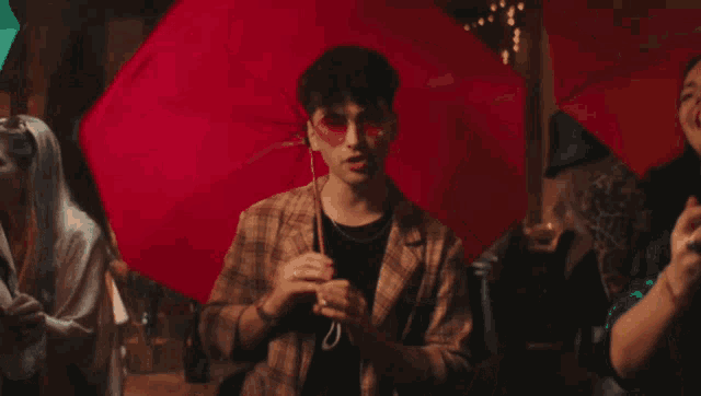 a man holding a red umbrella in front of a crowd