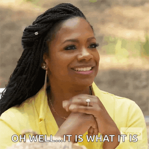 a woman in a yellow shirt is smiling and says " oh well it is what it is "