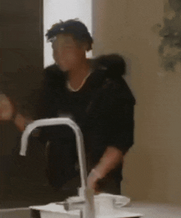 a man is standing in front of a sink in a kitchen and washing his hands .