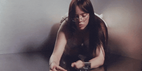 a woman wearing glasses and a watch is sitting on a couch .