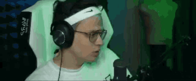 a man wearing headphones and a nike headband is sitting in a chair .