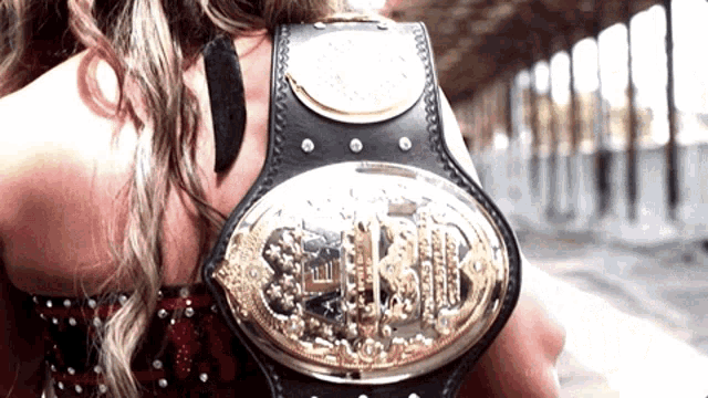 a woman is holding a championship belt with the word slb on it