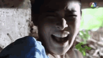 a close up of a person 's face with their mouth open and a blue shirt on .