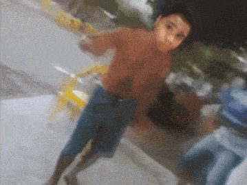 a man without a shirt is standing on a sidewalk pointing at the camera