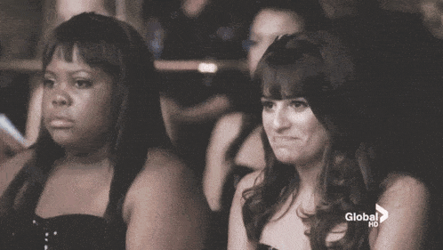 a group of women are sitting in a theatre and one of them is making a face