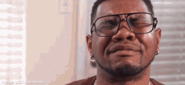 a man with a beard and glasses is crying and smiling .