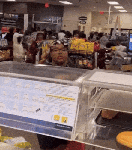 a woman behind a counter in a grocery store with a sign that says keep your hands to yourself