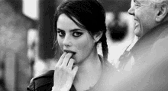 a black and white photo of a woman licking her finger .