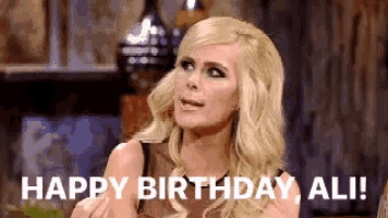 a blonde woman says " happy birthday ali " in front of her face